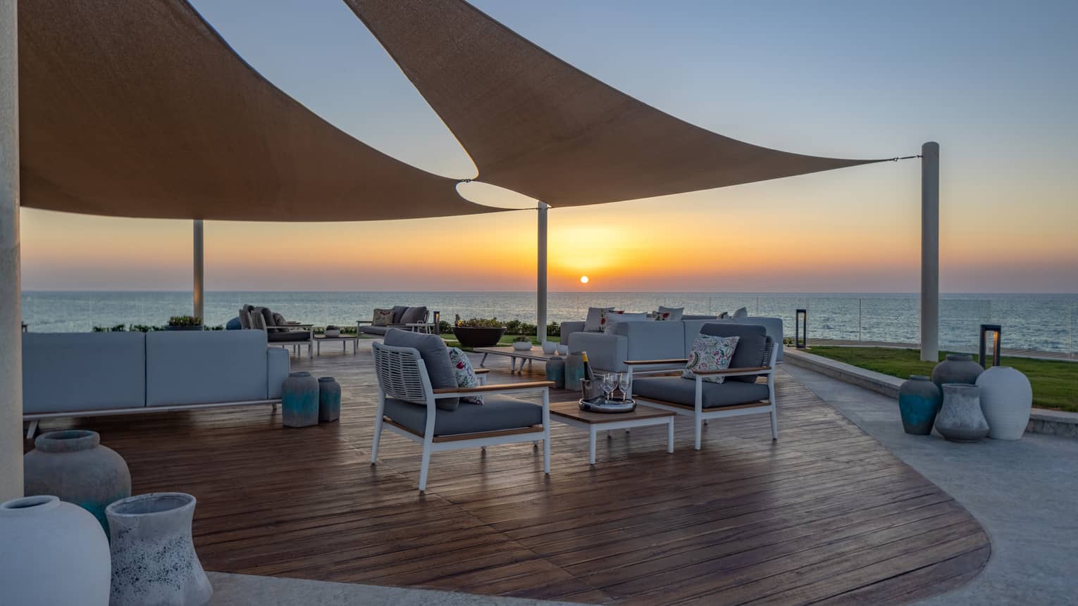 Partially covered patio of The Palace at sunset with lounge chairs and sofa