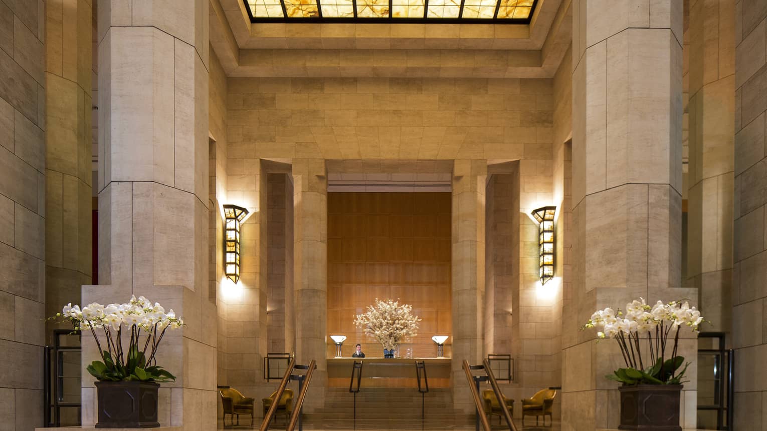 Tall marble columns, steps to hotel reception under amber skylight