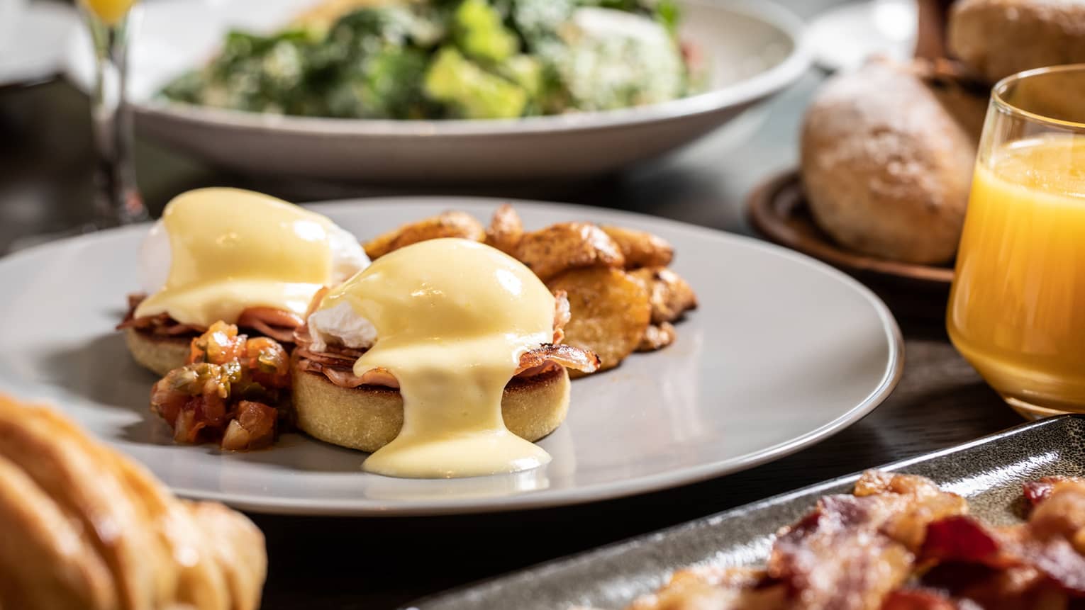 Sunday brunch table with Eggs Benedict, bacon and salad 
