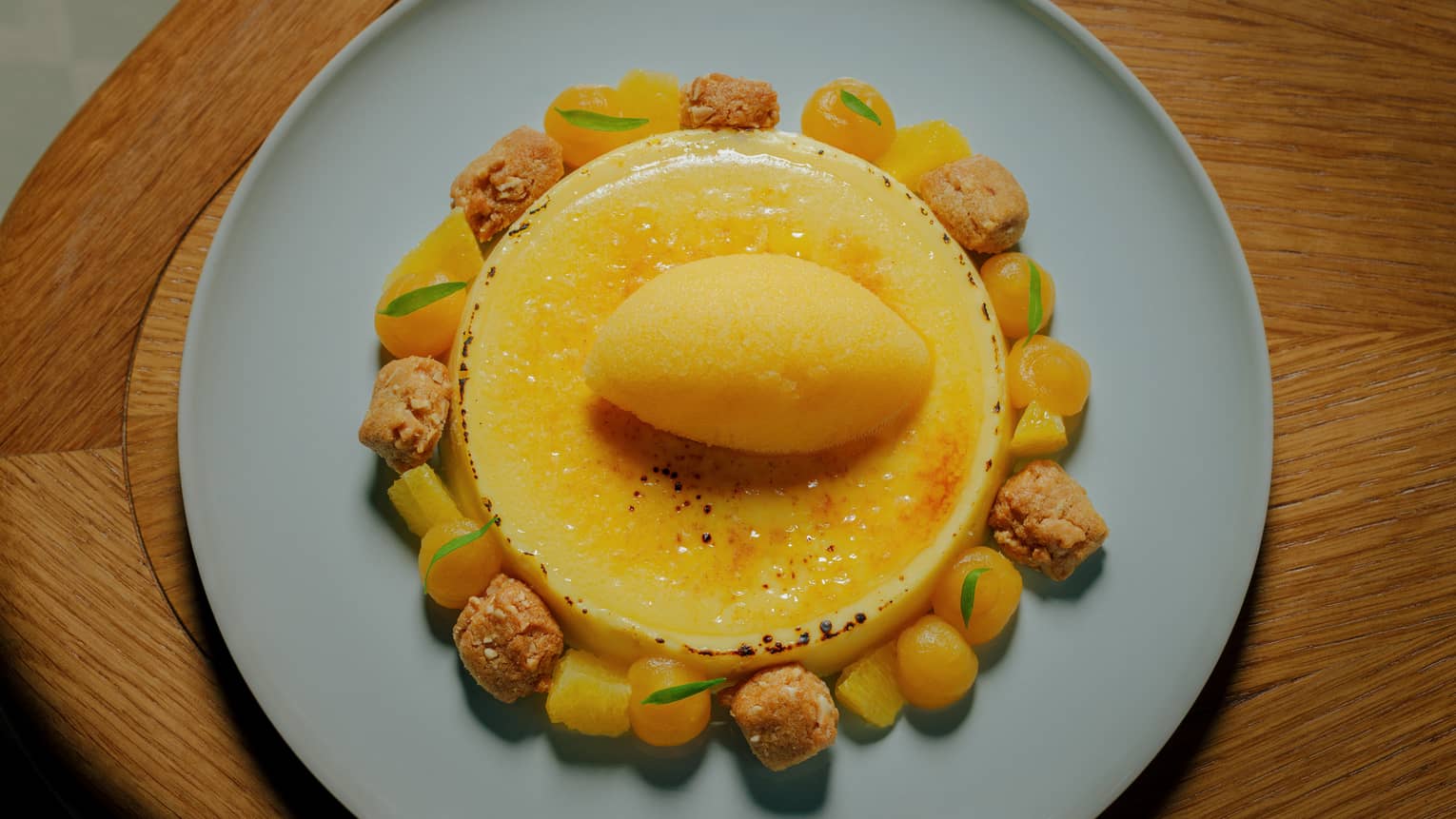 Cr�me Brulee served with orange sorbet, almond sable and orange gel on a light-blue plate