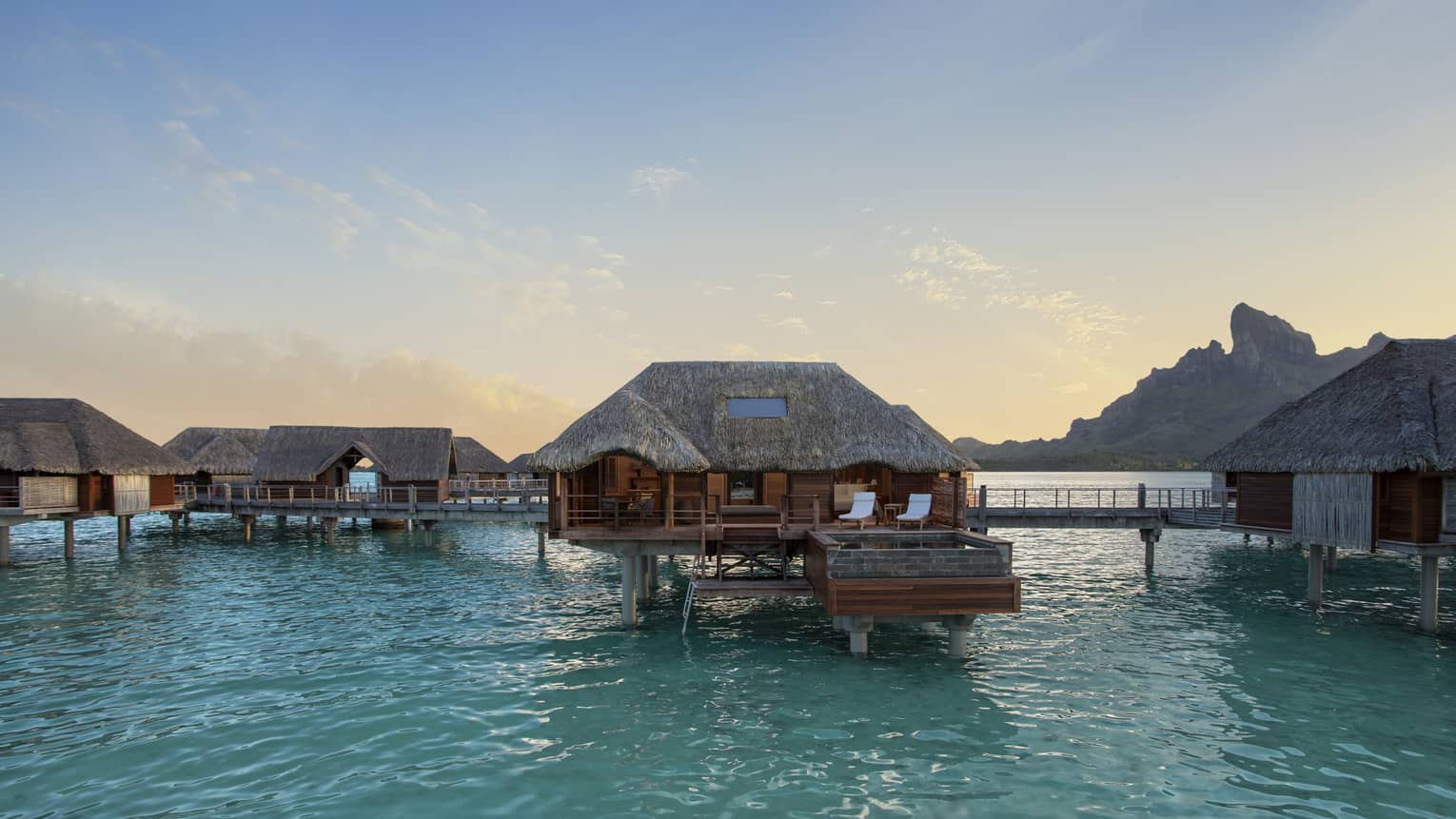 Over-water bungalows with thatched roofs at Four Seasons Resort Bora Bora