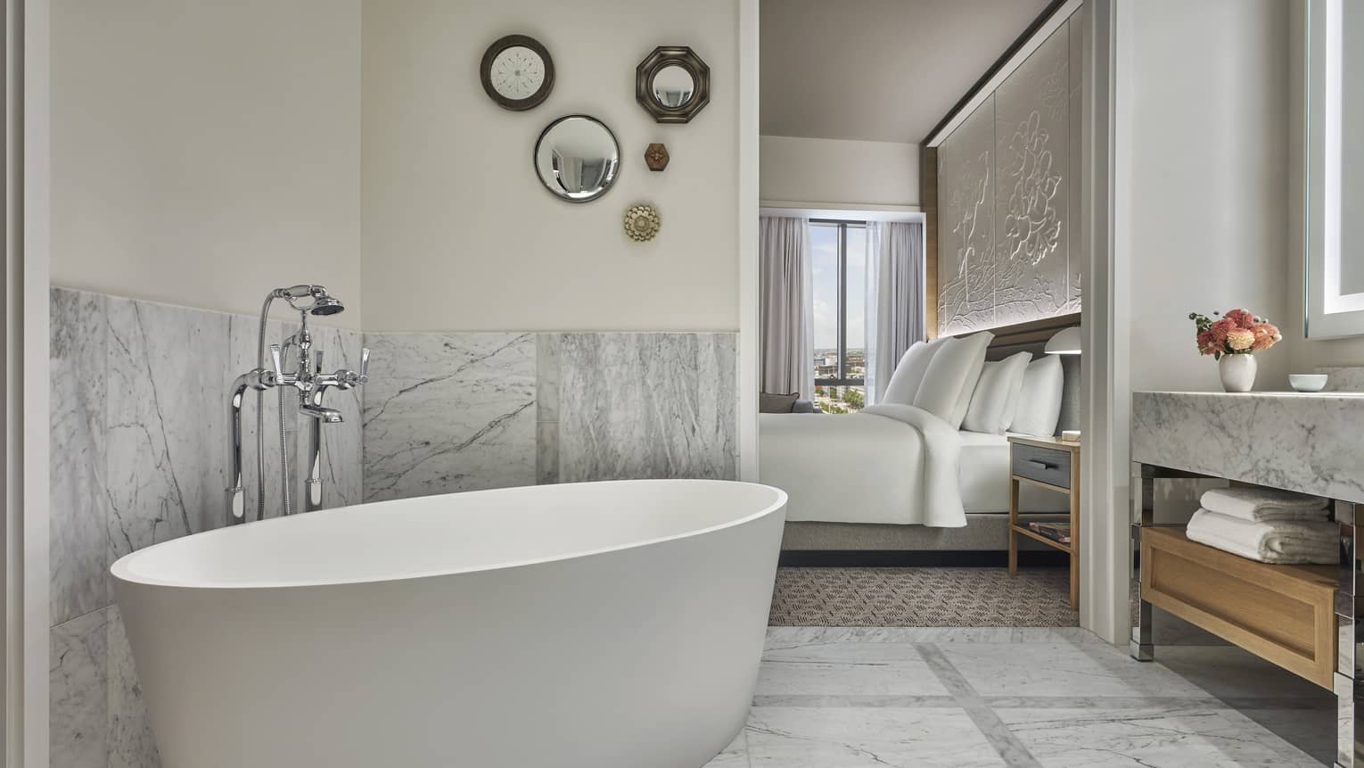 Premier King bathroom with marble counters and floors, large soaking tub, lighted mirror, wooden under-sink storage with towels