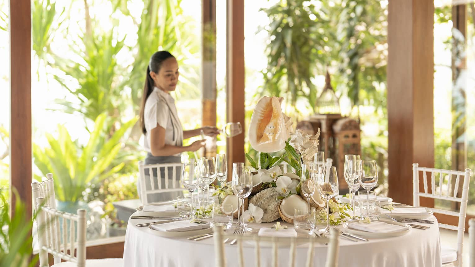 Female staff member sets table with large conch shell centrepiece for a banquet