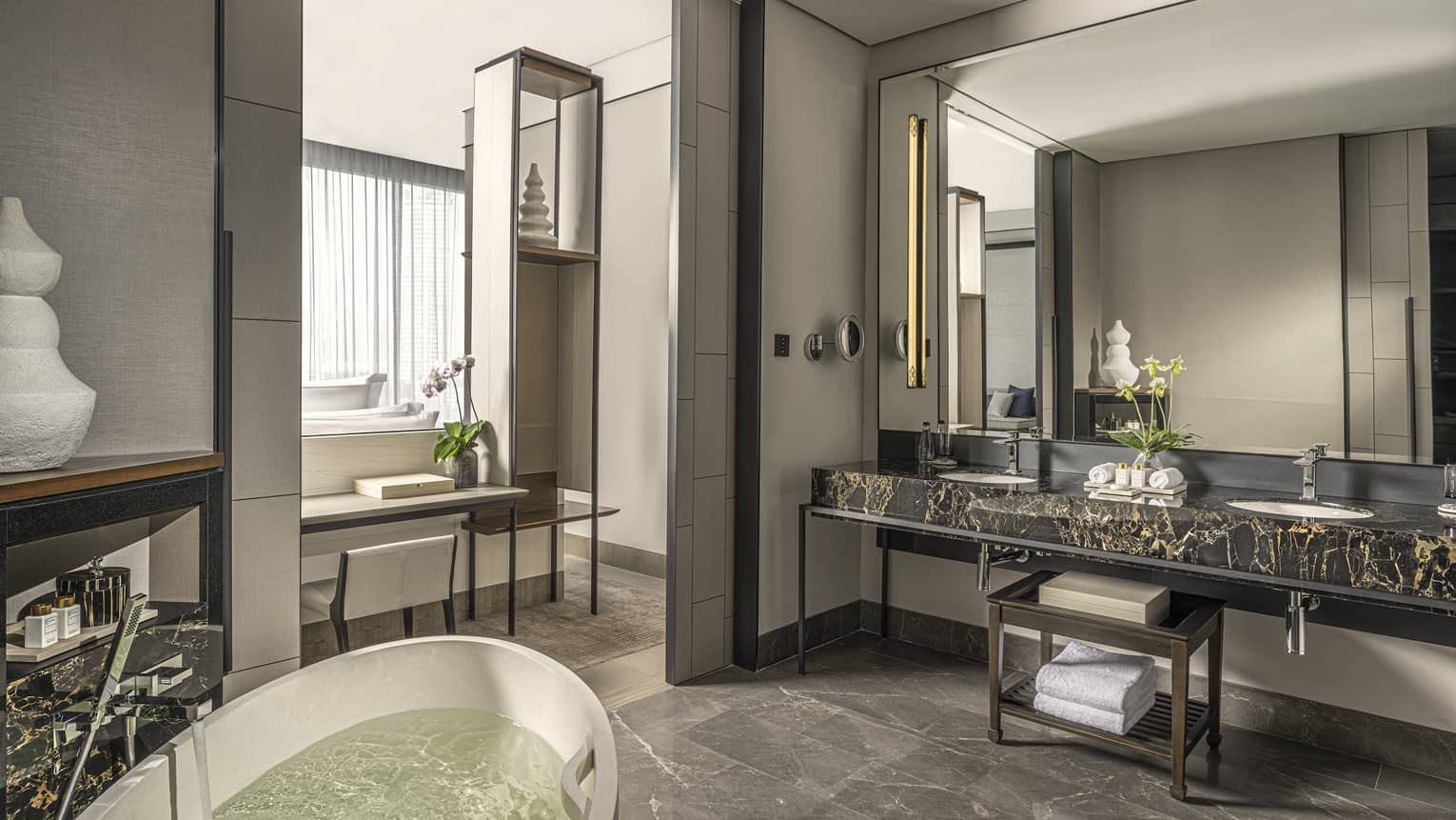 Bathroom, large mirror over black marble double vanity, standalone white tub, opening to bedroom