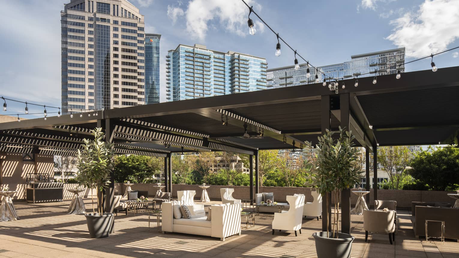 Fifth-floor rooftop terrace during the day with modern white sofas under large wood pergola