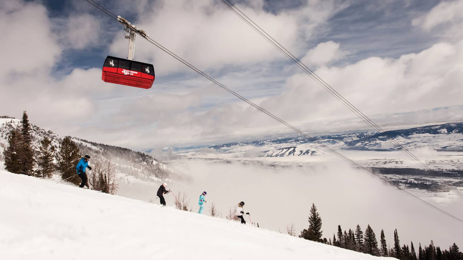 Red Sweetwater Gondola ski lift on wire above hikers on snowy mountain