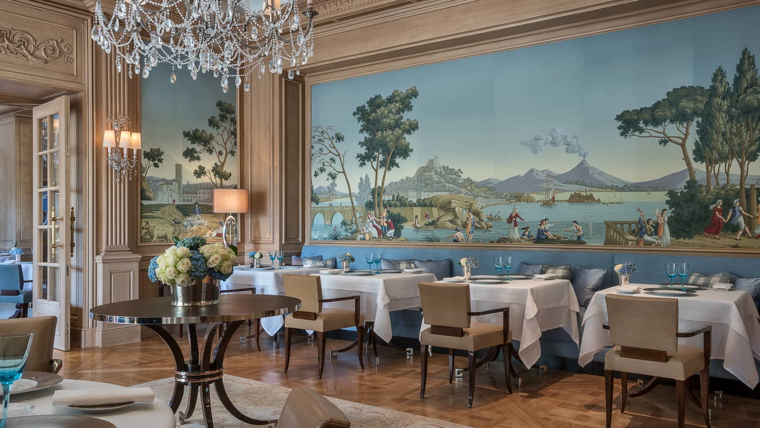 Il Lago elegant Northern Italian dining room with wall-sized mural above tables, chairs, crystal chandelier