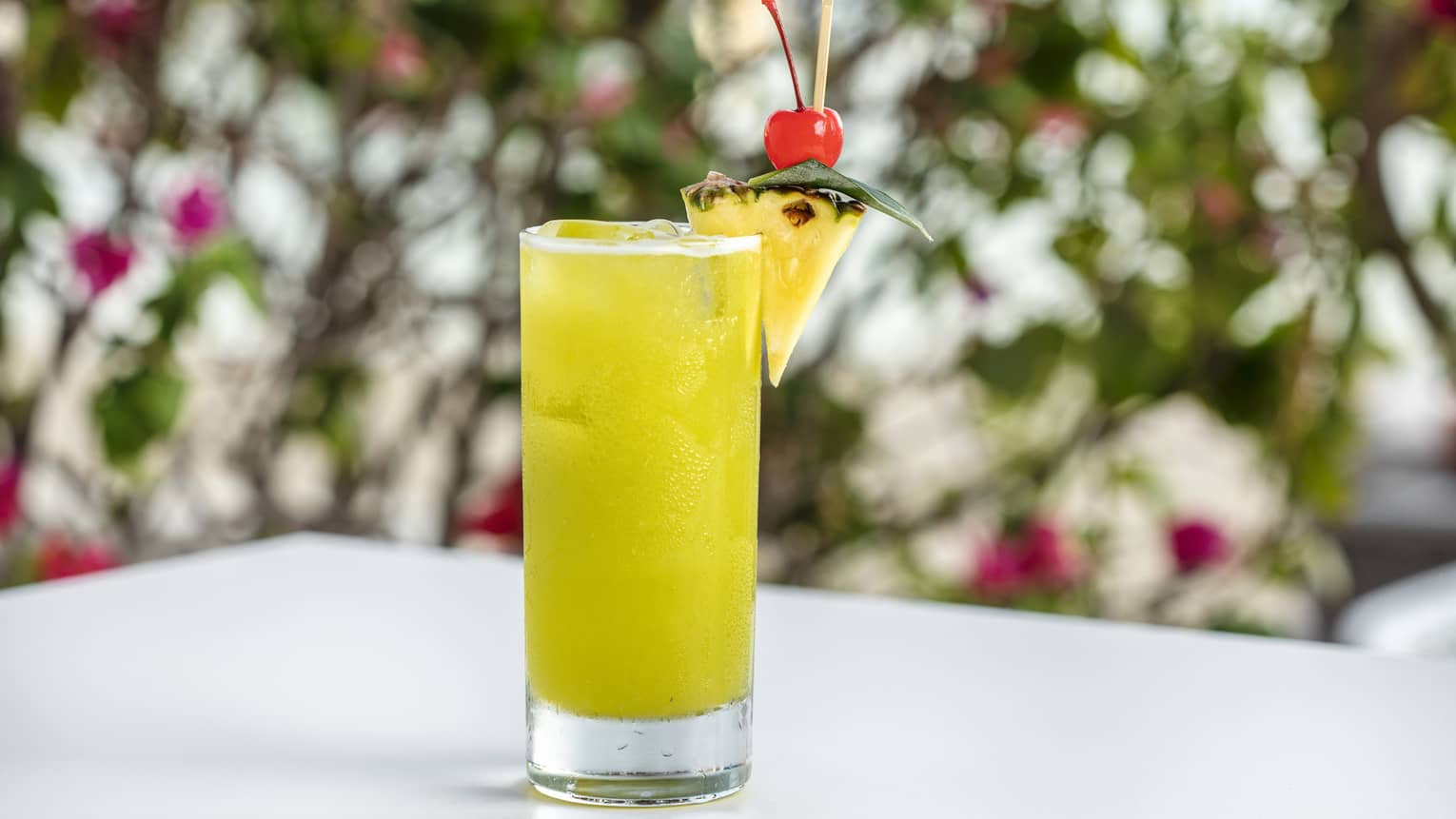 Seabreeze in a high ball glass garnished with a piece of pineapple and a cherry