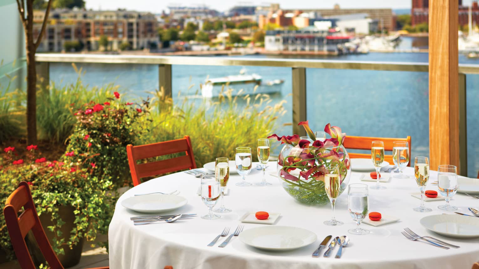 Round outdoor dining table with Champagne glasses on patio overlooking river