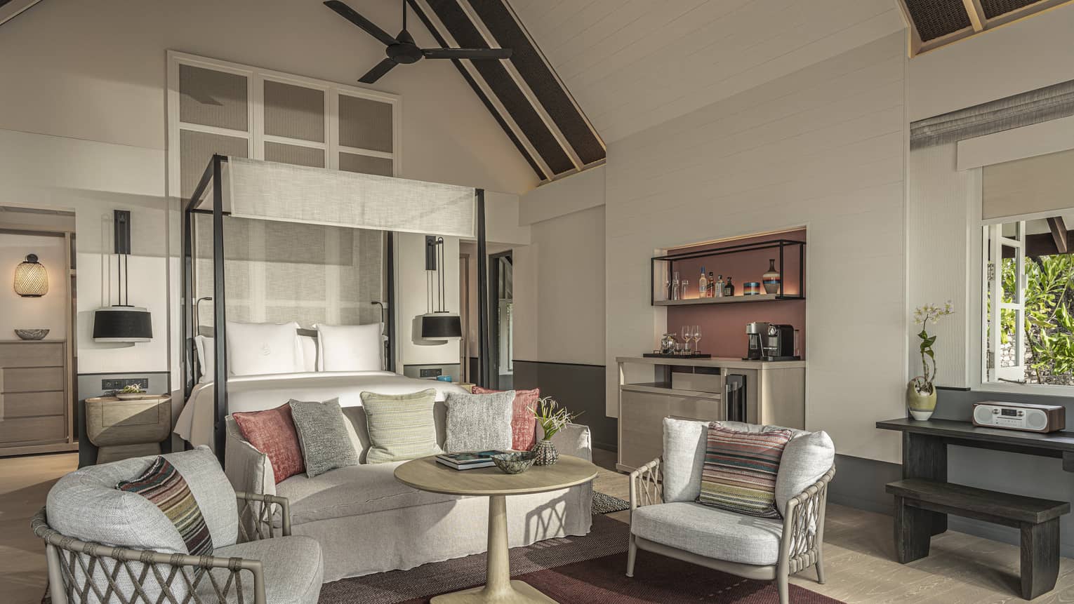 Master bedroom with canopy bed, sofa and two chairs, with vaulted beamed ceiling