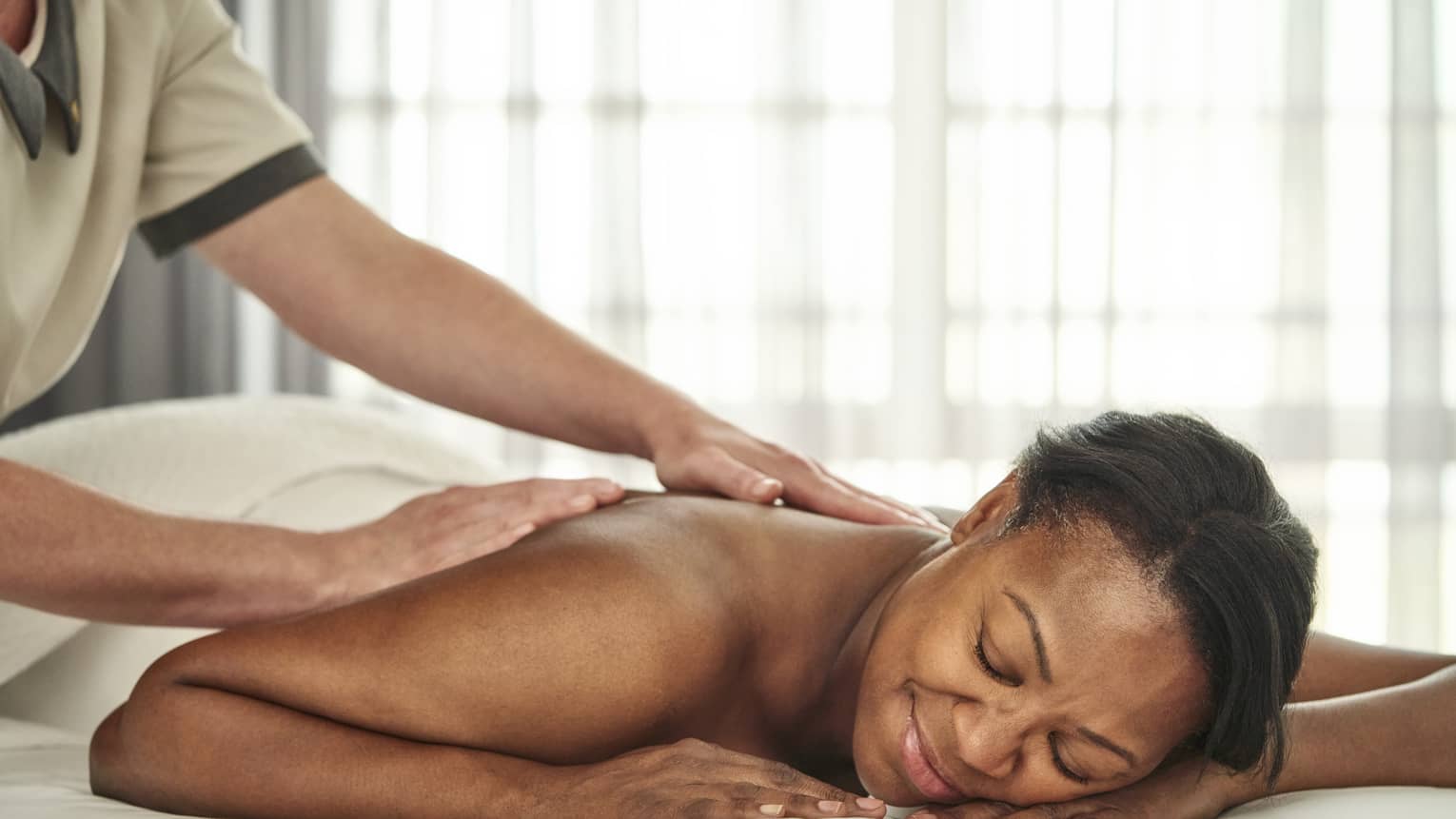 A person getting a massage in a well lit treatment room.