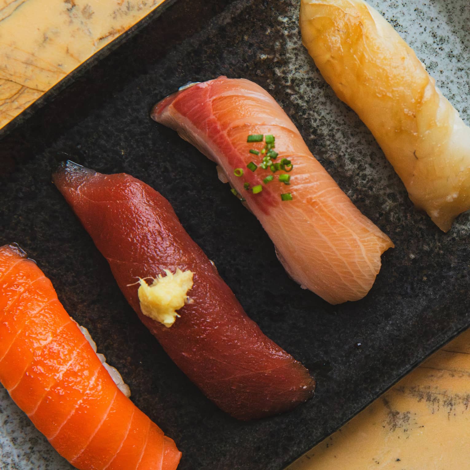 Sashimi on a black tray next to a 17-course menu