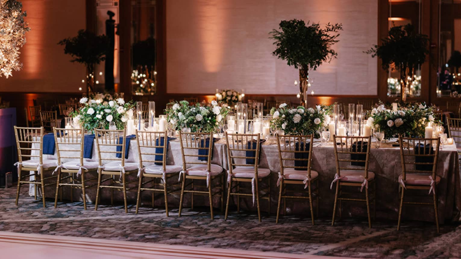 Long rectangular table set up for wedding reception with white lines and white and green florals