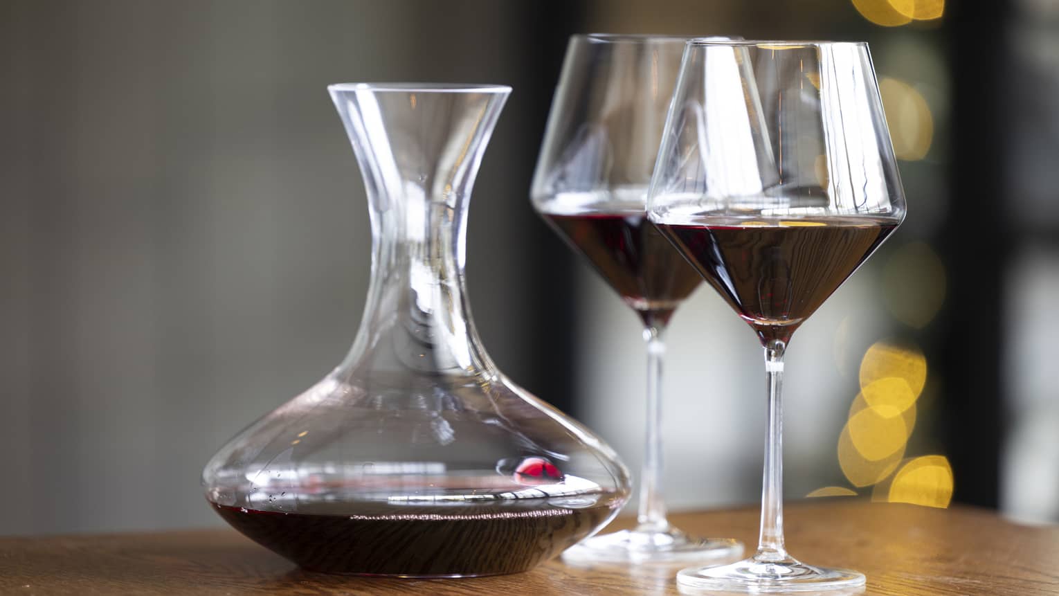Two wine glasses on a table beside a wine pitcher