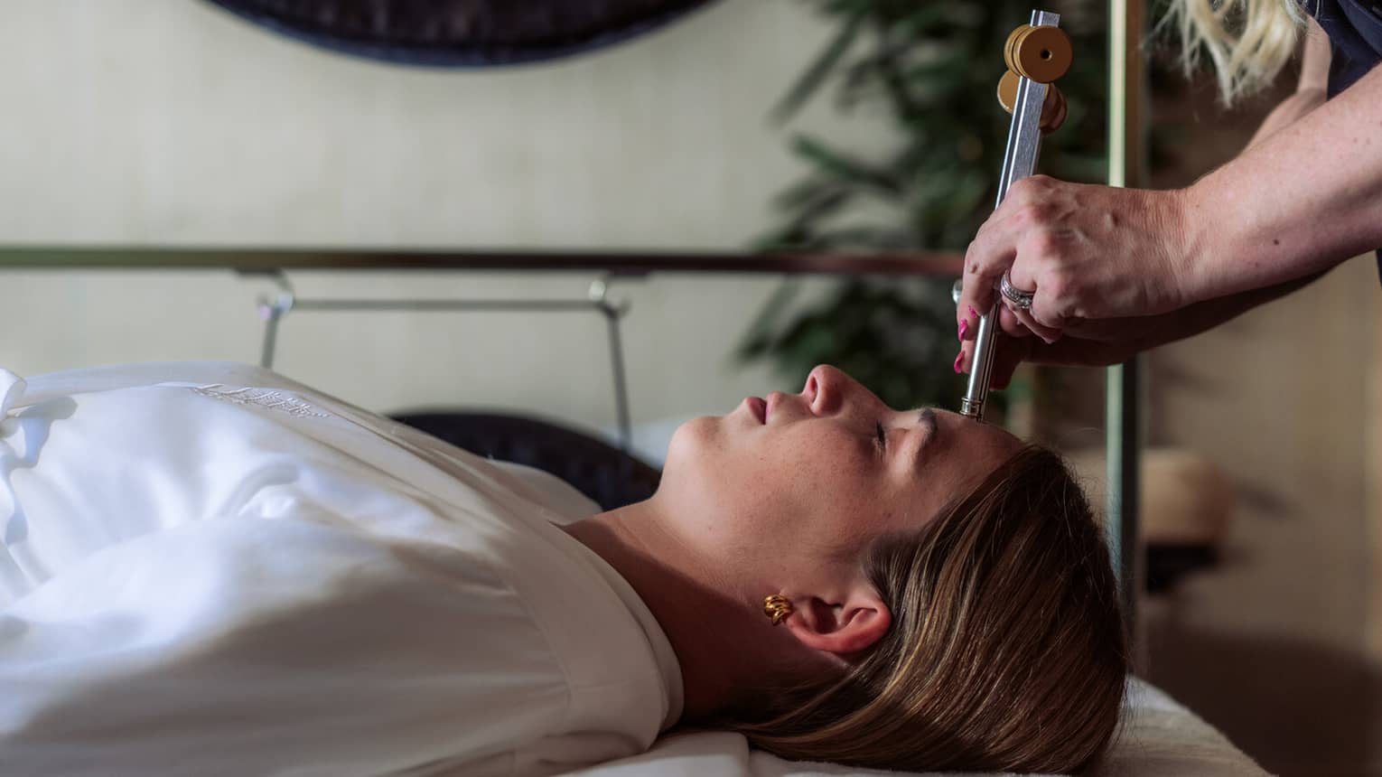 A woman receiving sound healing treatments at a spa.