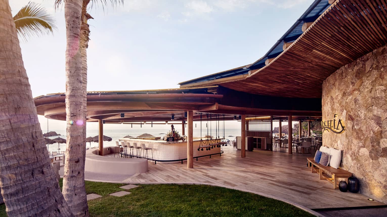 An outdoor bar area next to grass and palm trees.