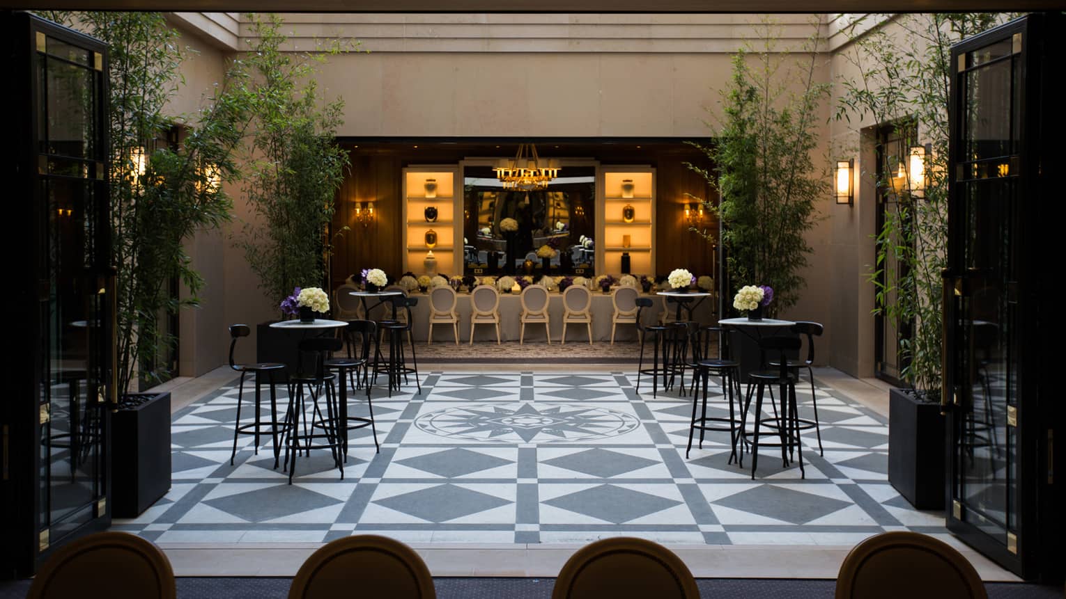 Small cocktail tables, bar stools in bright Marble Courtyard with blue and white tiles