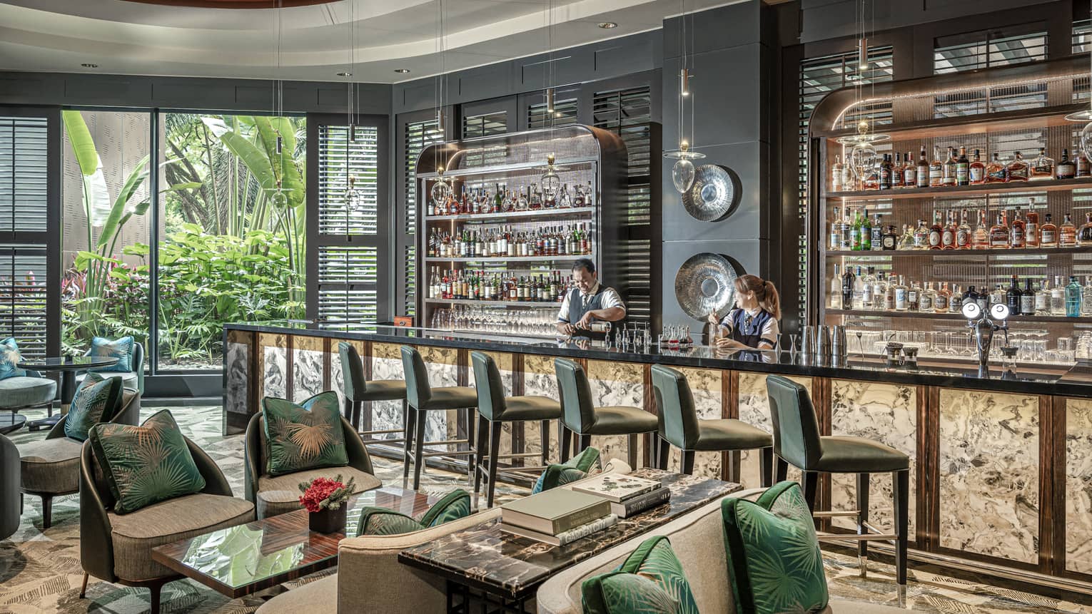 Male and female bartender stand behind counter at light-filled One-Ninety Bar