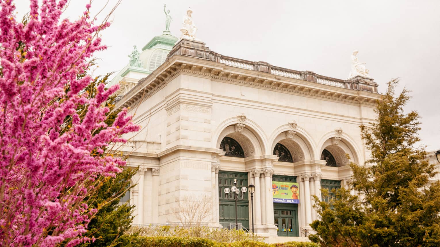 The exterior of a children's museum with large pink and green plants on the outside.