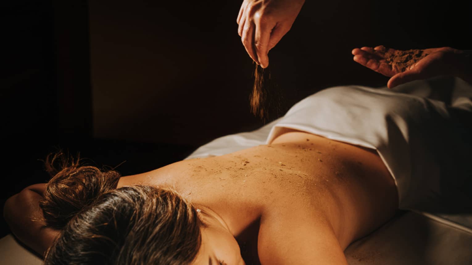 A guest in the 'Iliahi body cocoon, being moisturized with coconut oil and sprinkled with sandalwood powder