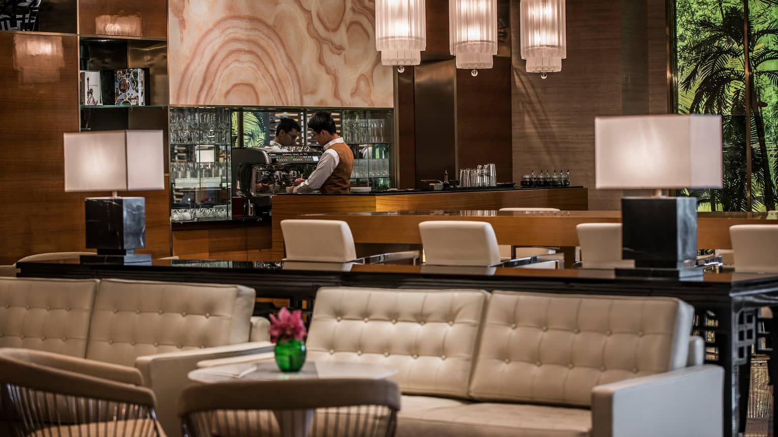La Sala staff makes coffee at espresso machine behind wood bar, white leather banquettes