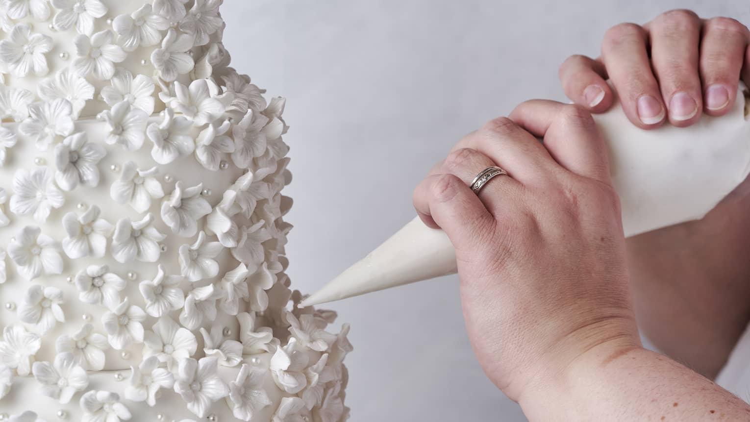 A person putting icing on a tall cake.
