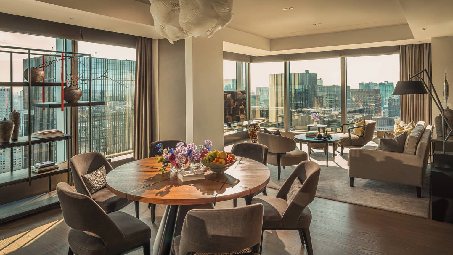 Luxury hotel suite featuring a living room and dining room with two walls of windows looking out to city view