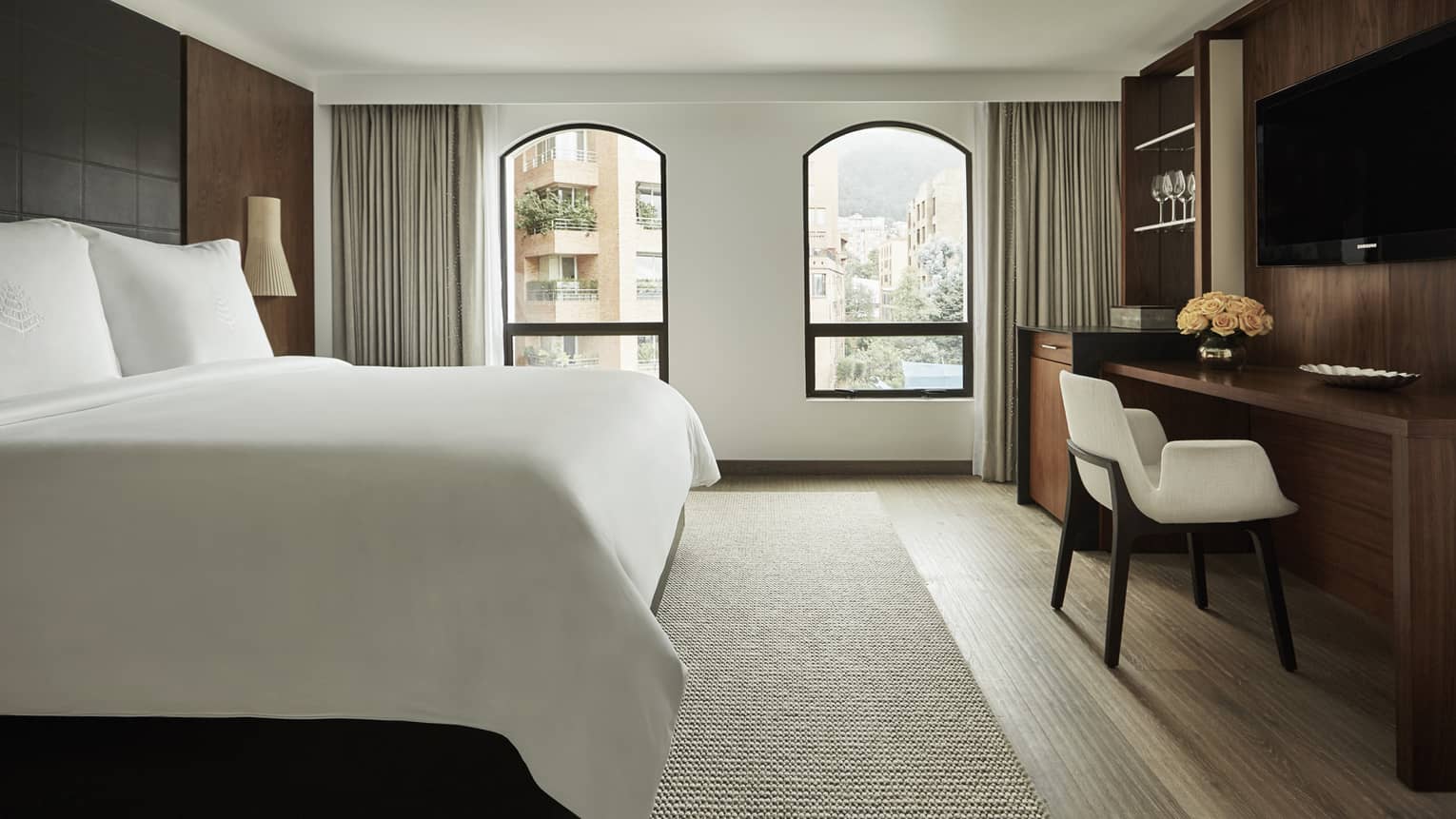 Superior Room bed, two windows with sunny city view, flat-screen TV over wood desk with white chair