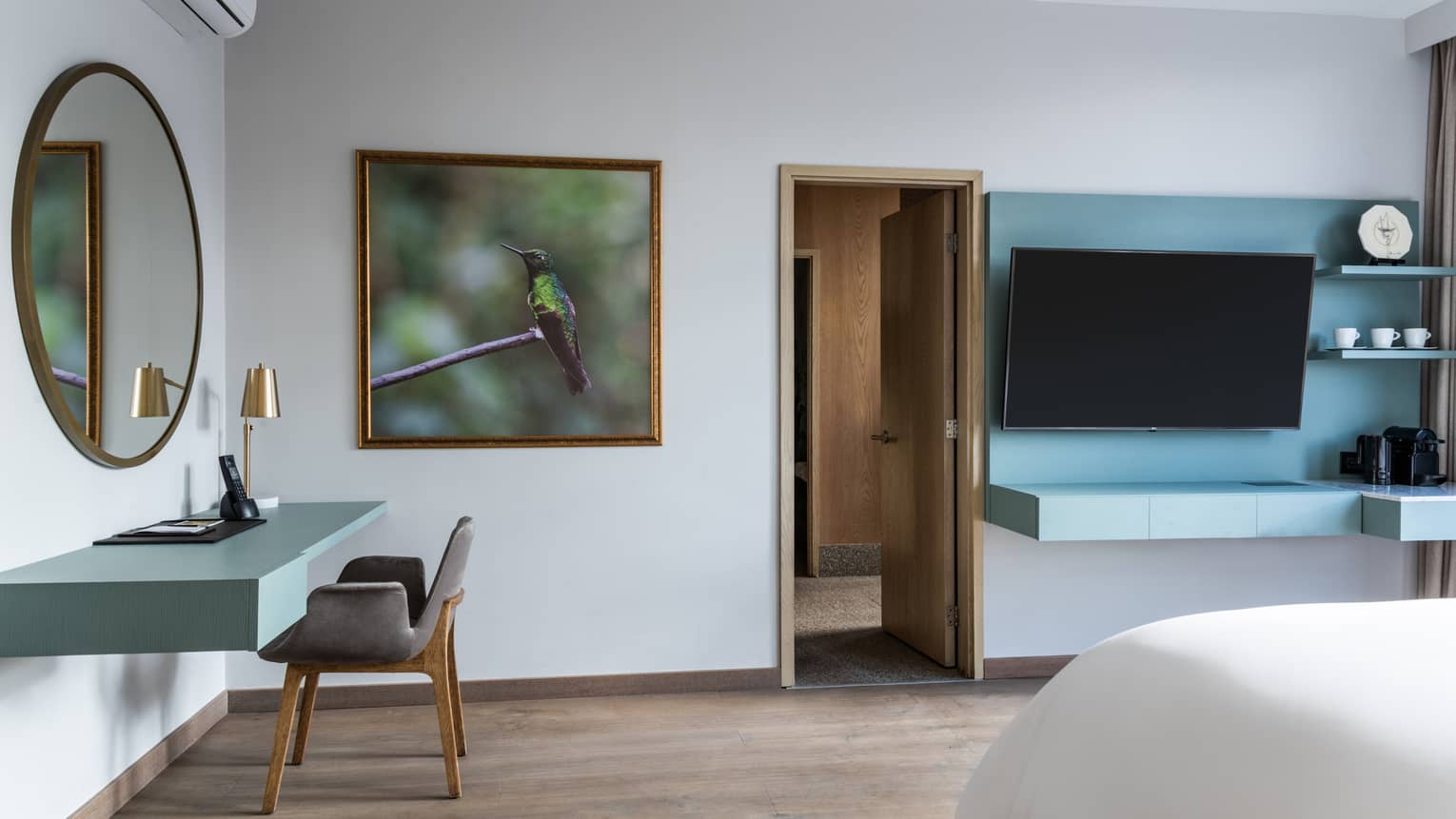 A small green desk and chair in the corner of a spacious bedroom.