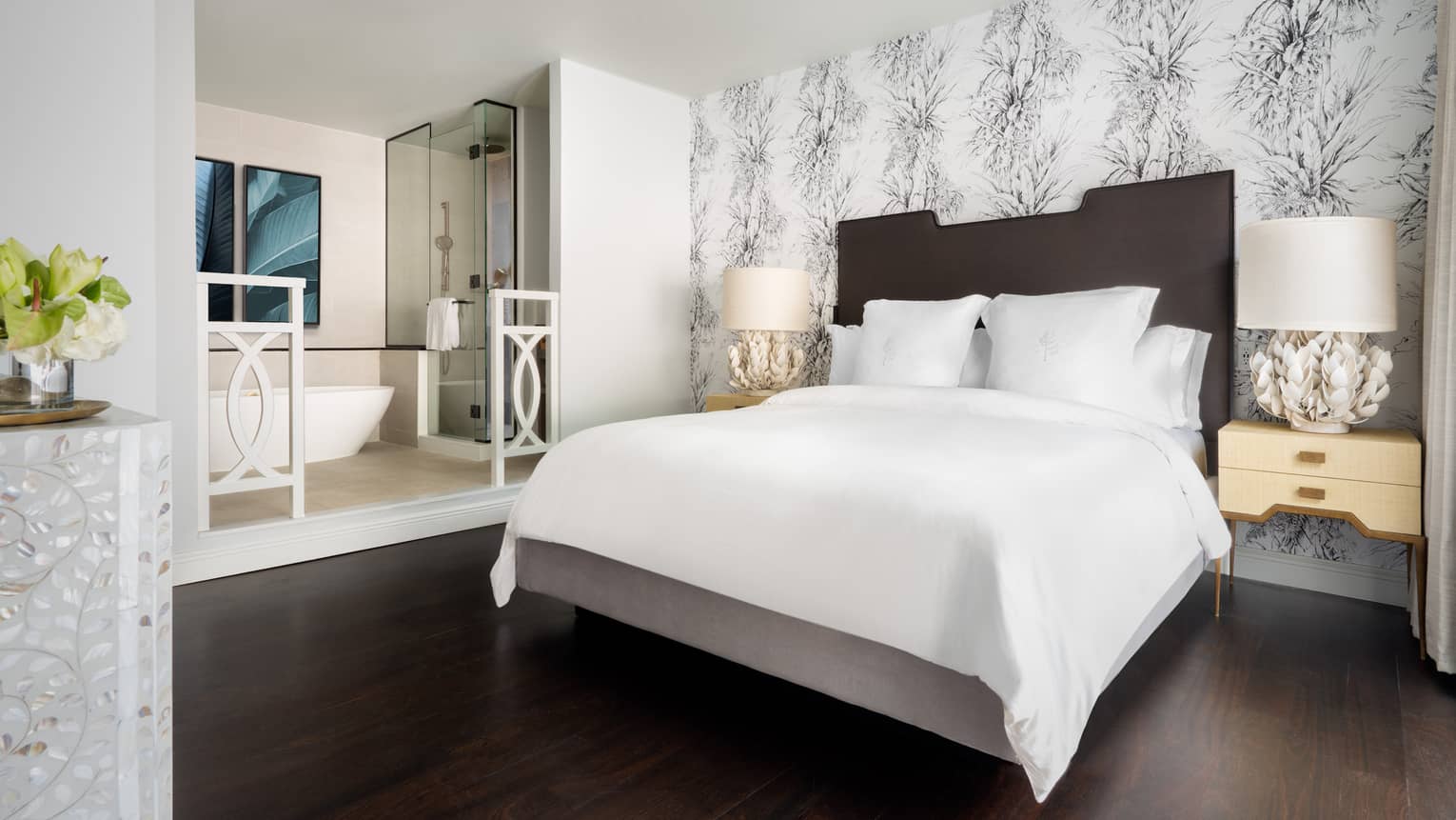 Resort room with a queen bed, modern decor and an open bathroom featuring a freestanding bathtub