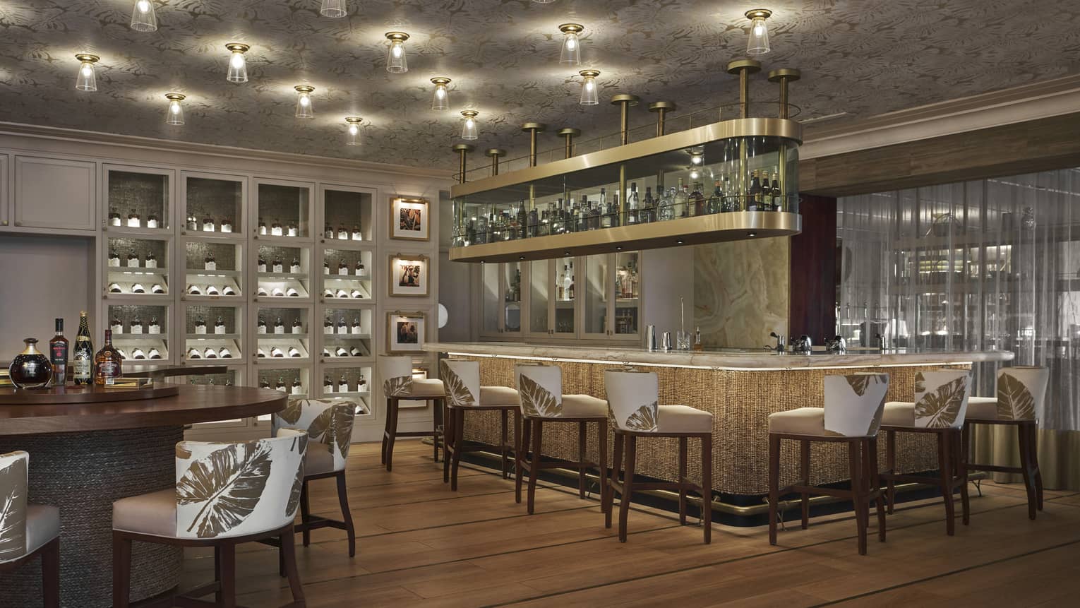 A dimly lit bar area with a large bar and white stools.