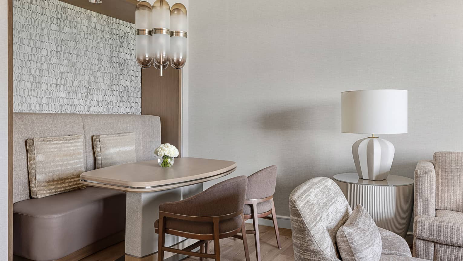 Dining table four four, with wall booth seating and two chairs, in a neutral-coloured living room
