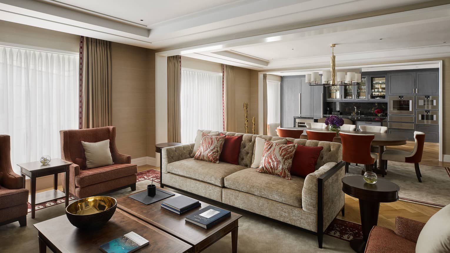 Plush sofa with cushions, pink armchairs and pillows in front of dining room