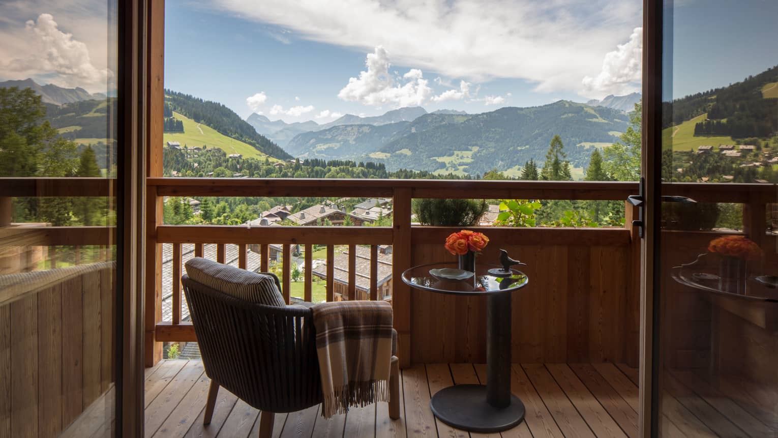 Suites des Alpes patio chair with blanket, table with flowers on balcony overlooking French Alps