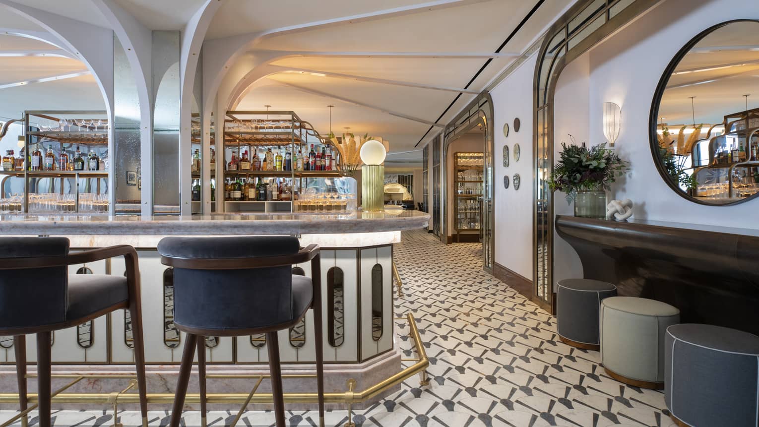 Miss River bar area with navy stools, against-the-wall seating area, patterned floor, liquor bottles on display in the background