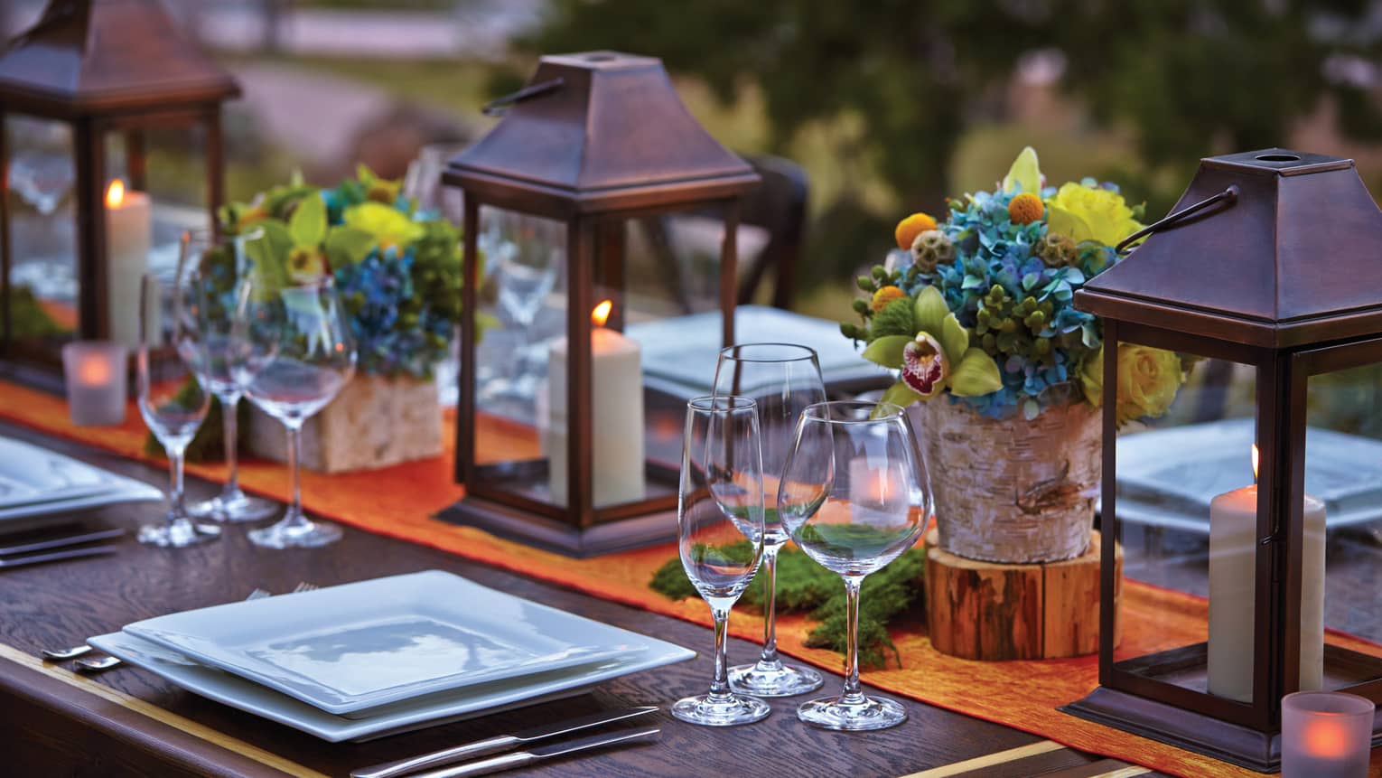 Close-up of lanterns, flowers on patio dining table at sunset