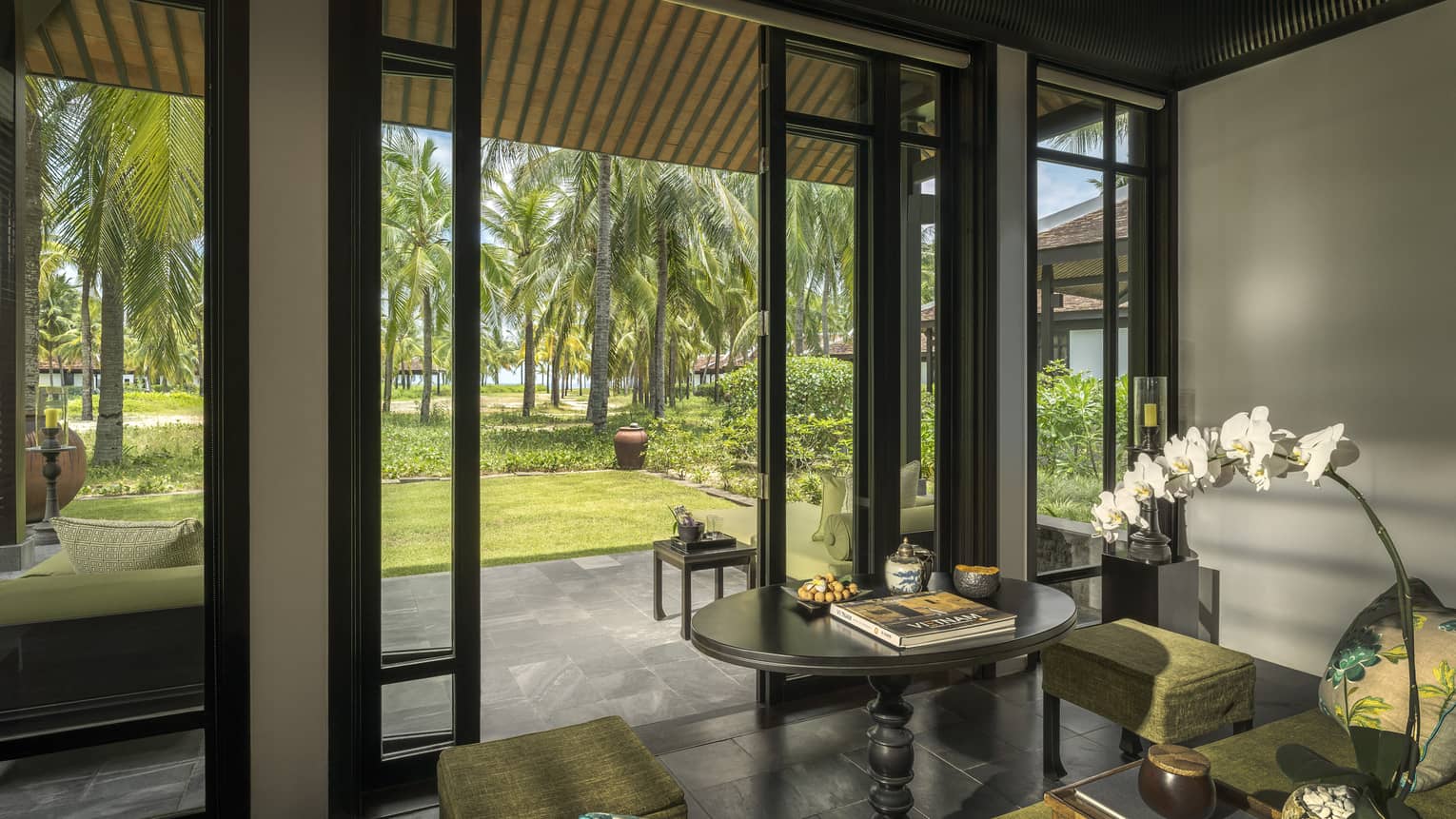 Family Villa living area opening on stone floor veranda with palm tree views