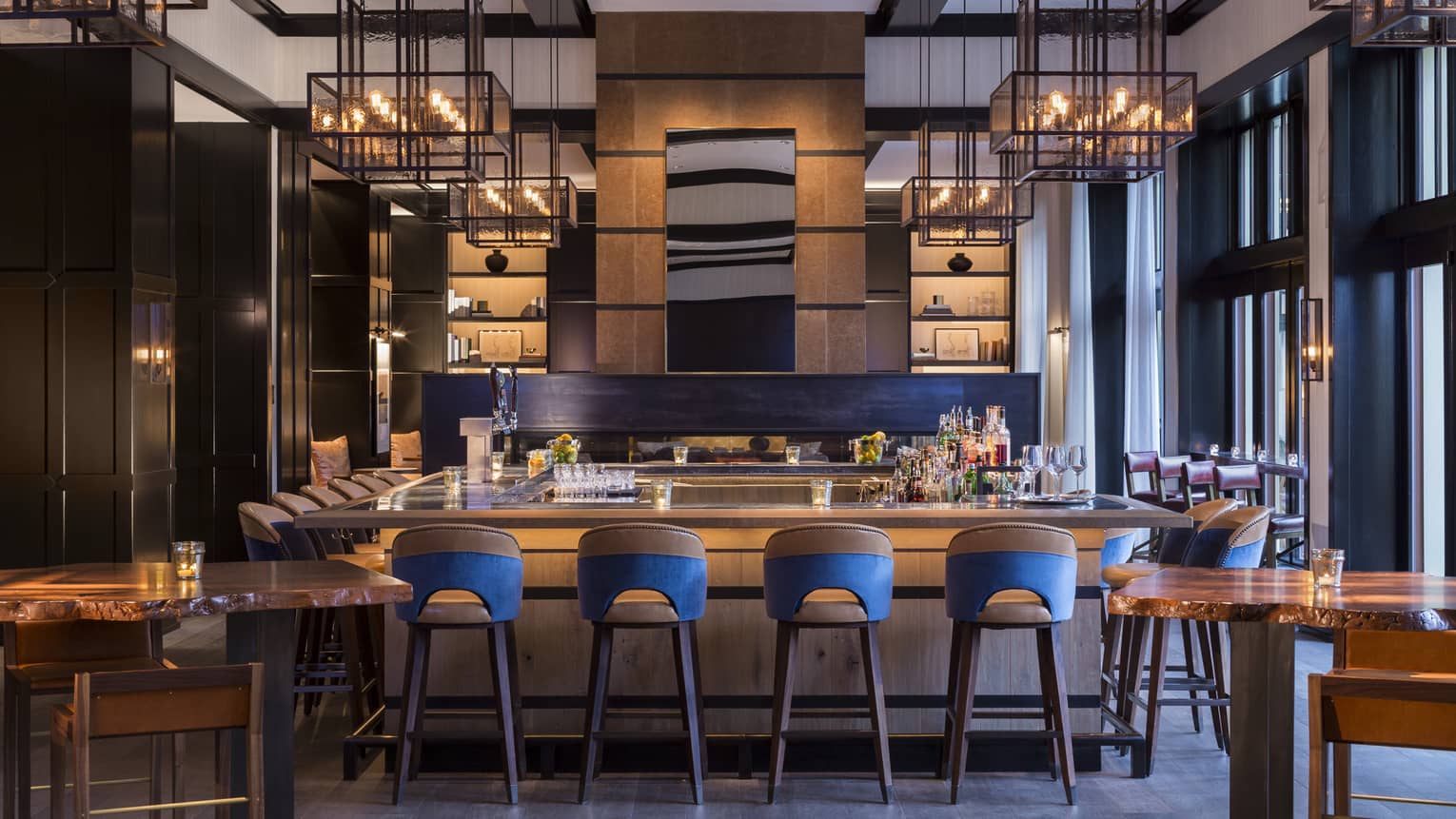 Blue and wooden bar stools surround wooden bar, contemporary lights 