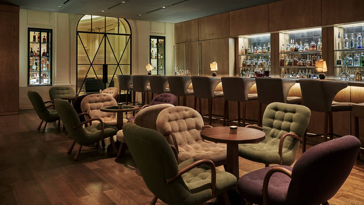 Cut Lounge plush, tufted dining chairs around small cocktail tables, stools line candle-lit bar