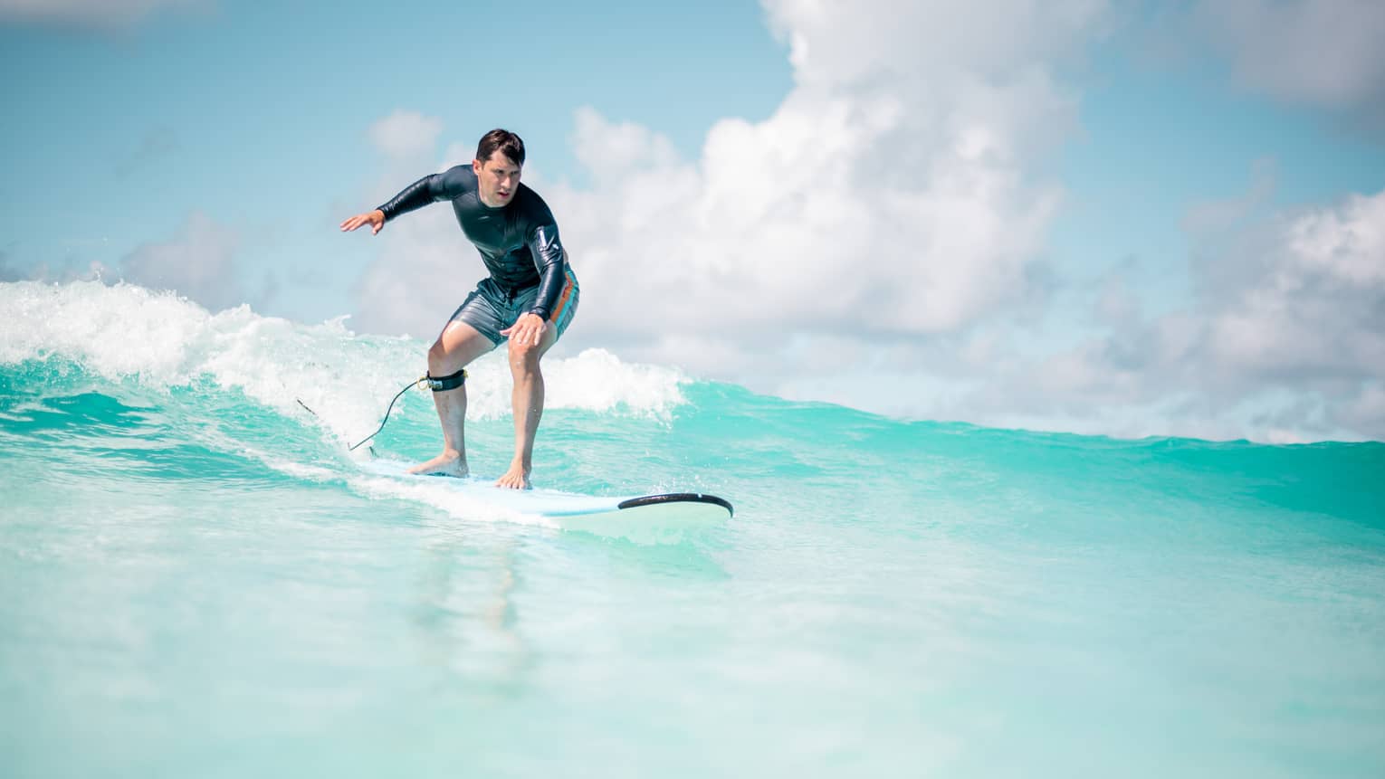 Man balances on surf board over wave