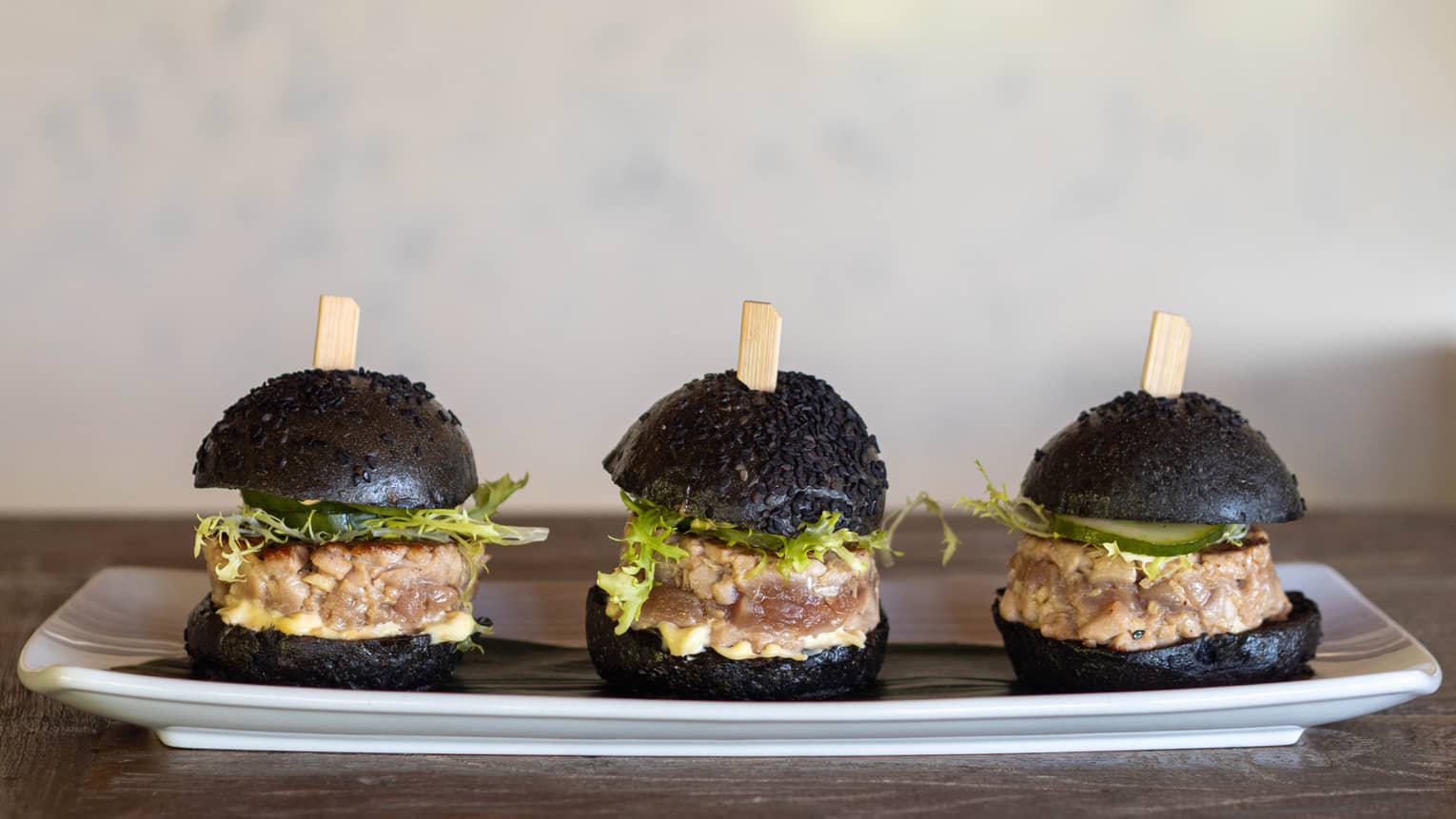 Small tune burgers with black buns.