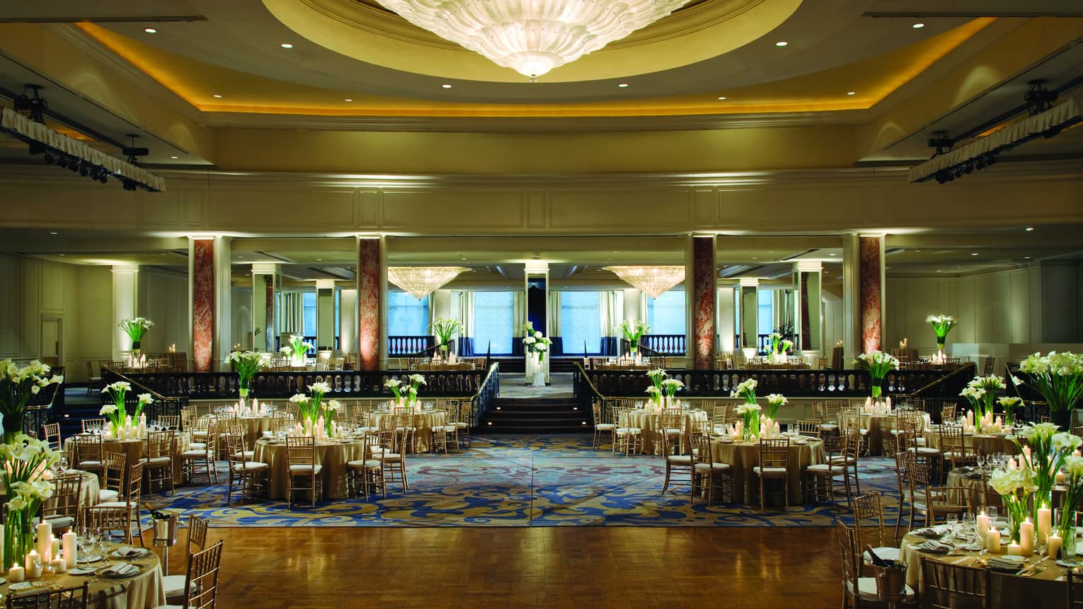 Ballroom dance floor under large cone-shaped crystal chandelier, round banquet tables