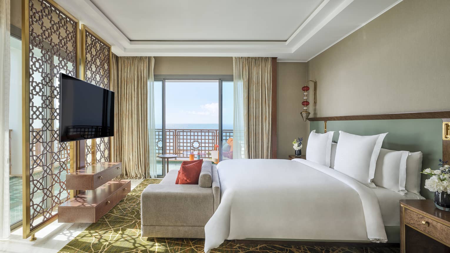 Luxury hotel suite bedroom with king bed, chaise, wrap-around sea-view balcony and TV at Four Seasons Hotel Rabat