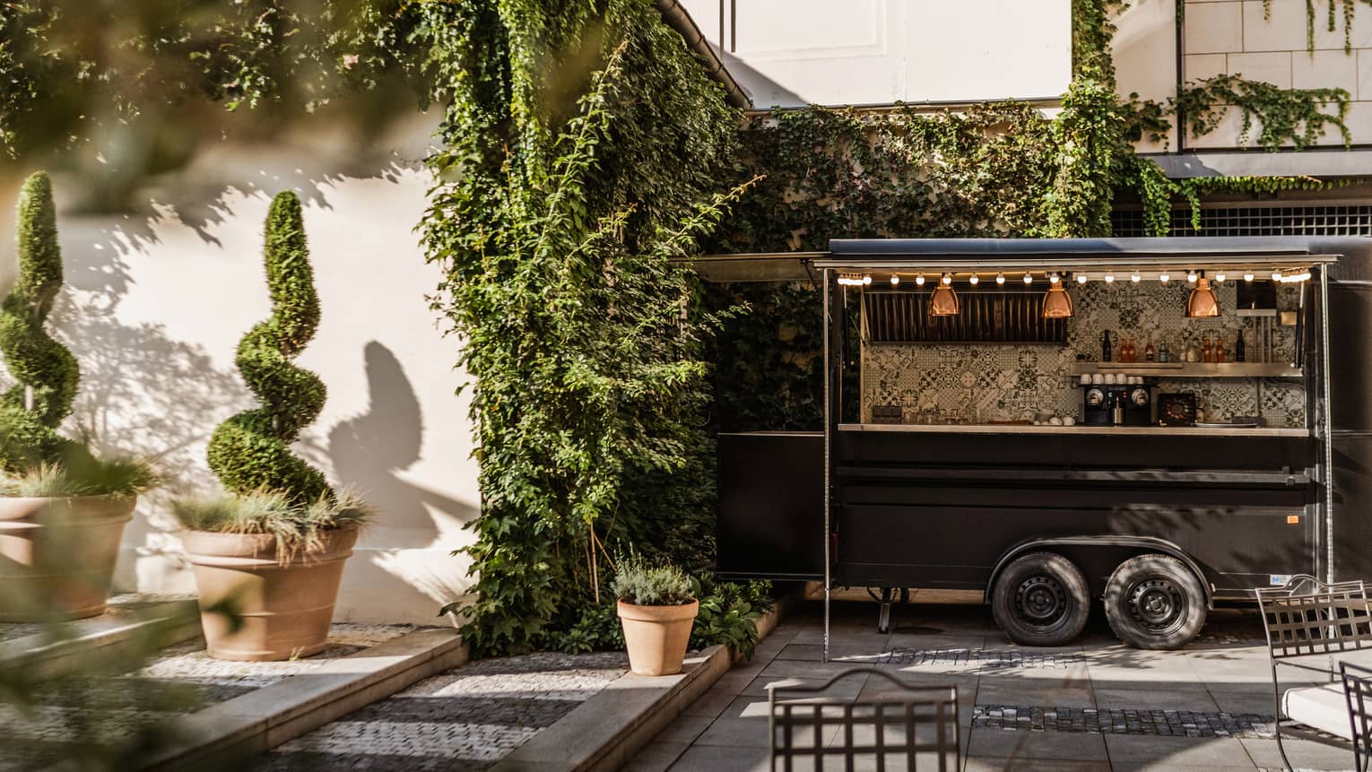 An outdoor event space with greenery-covered walls, decorative plantings and seating
