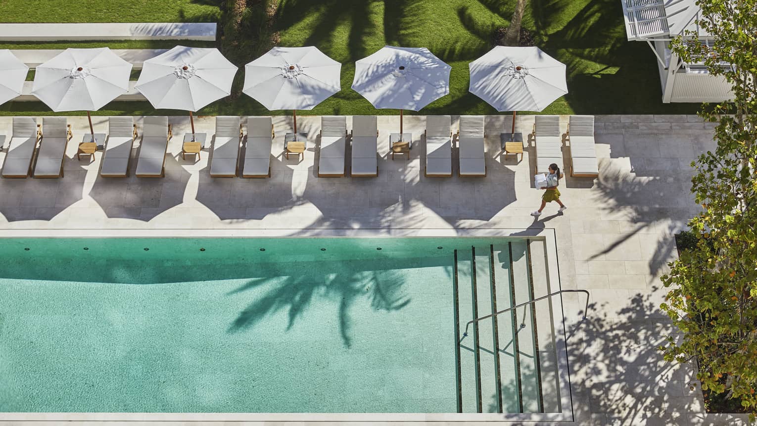 Aerial view of adult outdoor swimming pool, person walking across patio deck