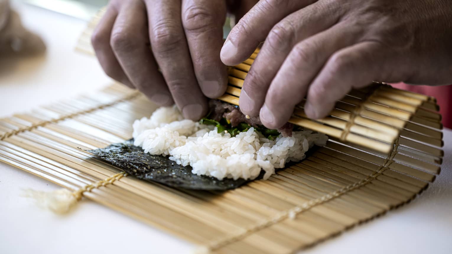 A four seasons chef rolls sushi with a bamboo mat 