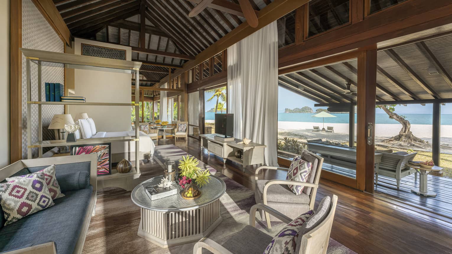 Teak living room opening to covered terrace with beach view