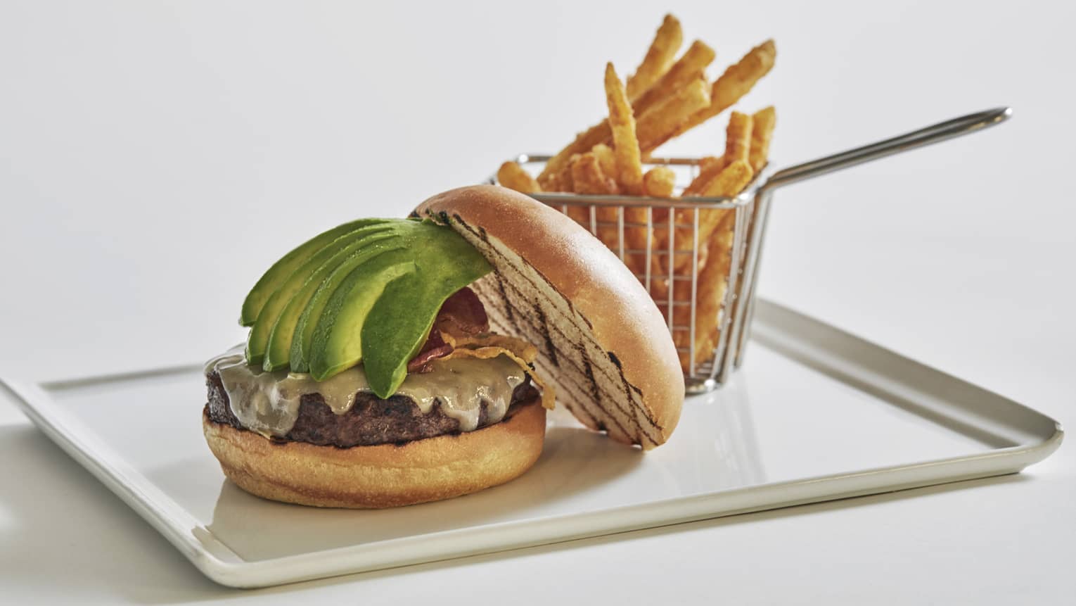 A beef burger with bacon jam, avocado and white cheddar, served with truffle parmesan fries