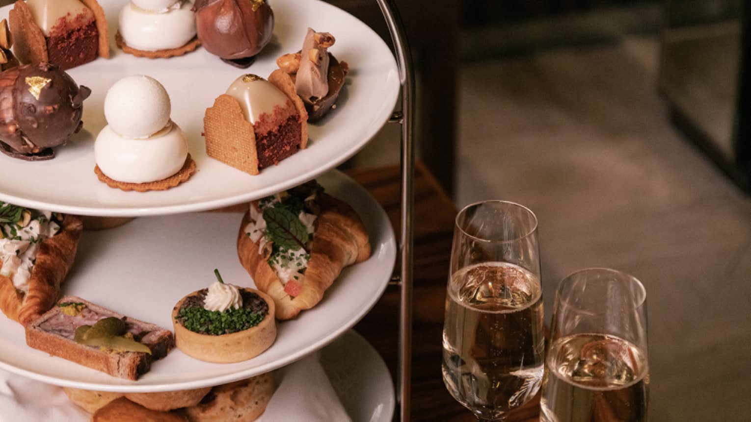 Three-tiered platter serving pastries and sandwiches for afternoon tea