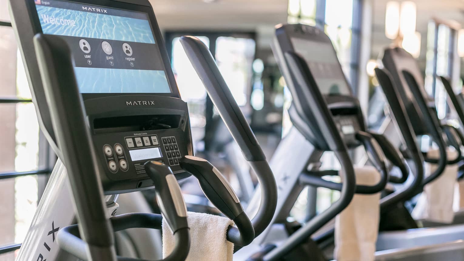 Close-up of Matrix cardio machine screens and handles in a row